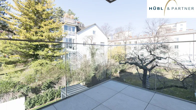 Geräumiger Balkon mit Fliesenboden und Glasgeländer bietet einen weiten Blick ins Grüne.