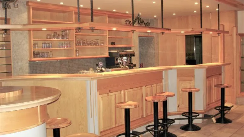Geräumiger Barbereich mit Holzverkleidung, Theke und Barhockern, ideal für gesellige Abende.