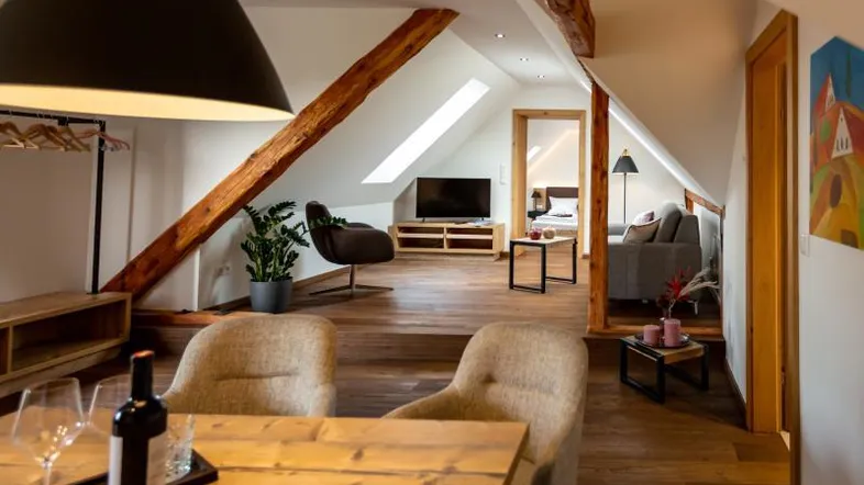 Gemütlicher Wohn- und Essbereich im Dachgeschoss mit Holzbalken, Dachfenstern und moderner Einrichtung.