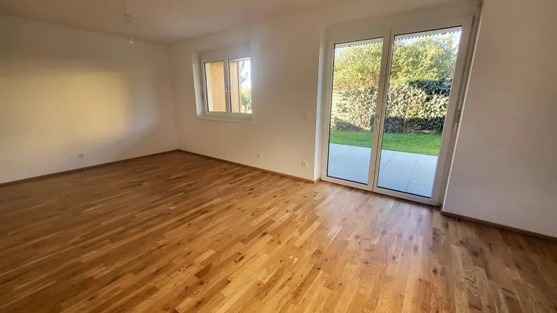 Helles Wohnzimmer mit Holzboden und Zugang zur Terrasse und zum Gartenbereich.