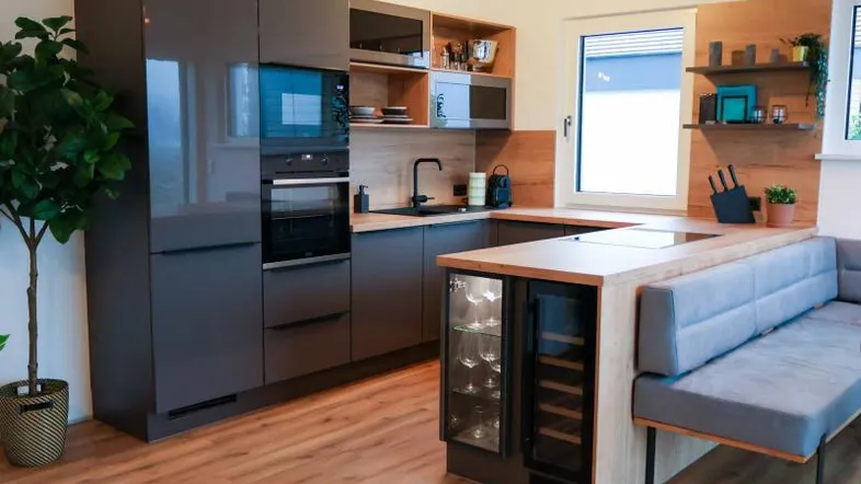 Moderne Küche mit grauen Hochglanzfronten, Holzakzenten und integriertem Weinkühlschrank.