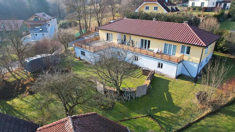Luftaufnahme eines gepflegten Hauses mit großer Terrasse, Garten und Blick ins Grüne.
