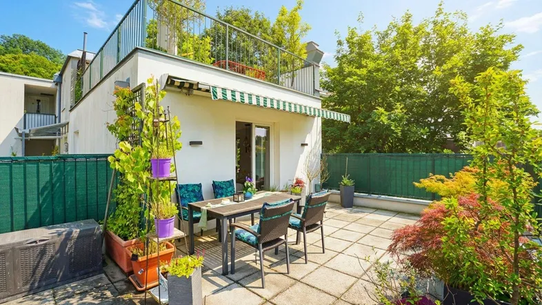 Sonniger Terrassenbereich mit Esstisch, Pflanzen und Blick auf die umliegende Natur.