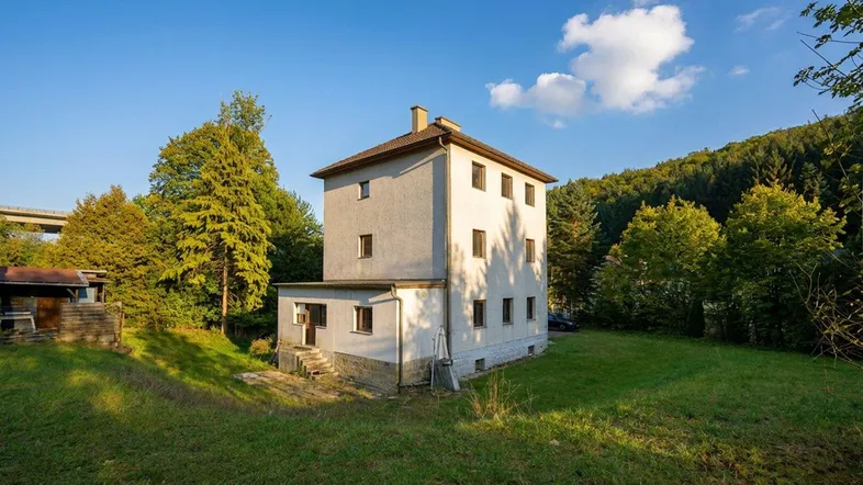 Freistehendes Haus in ländlicher Umgebung mit viel Grün und einem kleinen Nebengebäude.