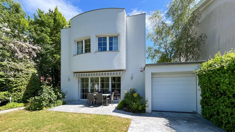 Moderne weiße Villa mit gepflegtem Vorgarten, Terrasse und integrierter Garage.