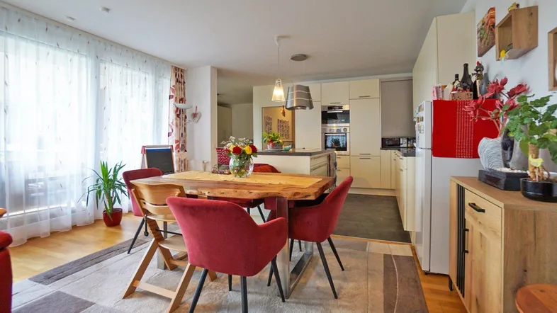 Heller offener Wohn- und Essbereich mit integrierter Küche und Holzboden, ideal für geselliges Beisammensein.