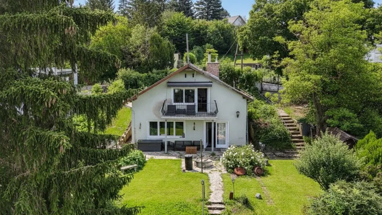 Freistehendes Haus mit großem Garten, Balkon und Terrasse, umgeben von viel Grün.