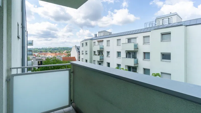 Blick vom Balkon auf die umliegenden Gebäude und die Stadtlandschaft unter blauem Himmel.