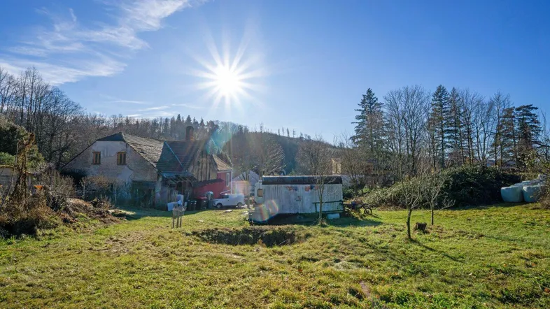 Ländliches Anwesen mit großem Garten und altem Haus unter strahlend blauem Himmel und Sonnenschein.