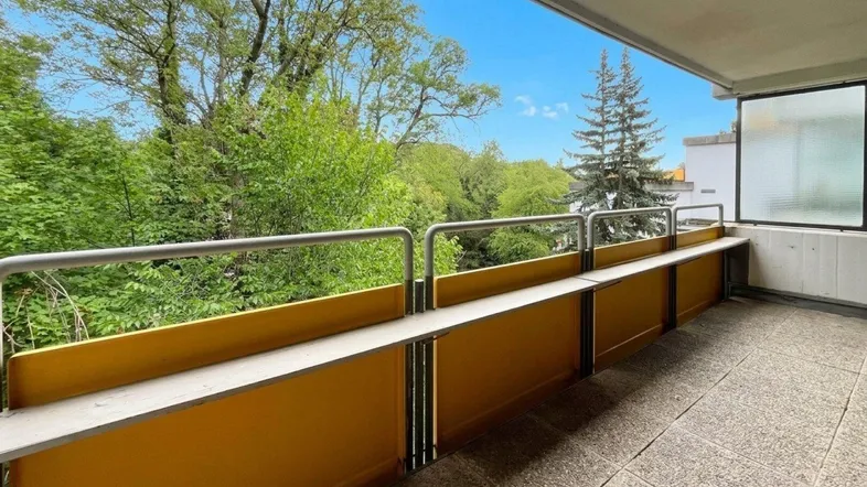 Geräumiger Balkon mit gelber Brüstung und weitem Blick ins Grüne.