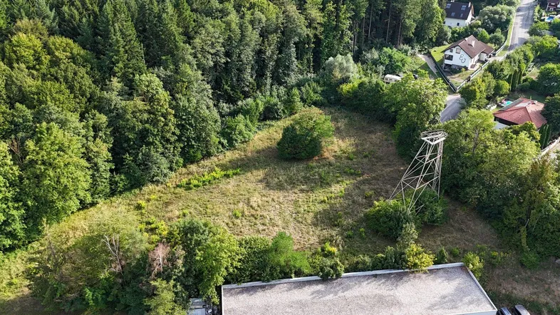 Luftaufnahme eines Grundstücks umgeben von dichtem Wald und einem angrenzenden Gebäude.