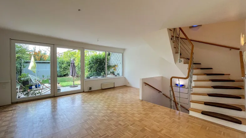 Heller Wohnbereich mit Parkettboden, großen Fenstern und direktem Zugang zum Garten.