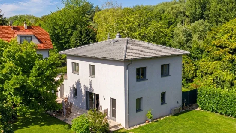 Modernes Einfamilienhaus mit gepflegtem Garten, großer Terrasse und umgebender Natur.