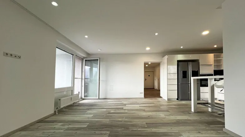 Heller, offener Wohnbereich mit moderner Küche, Laminatboden und Zugang zum Balkon.