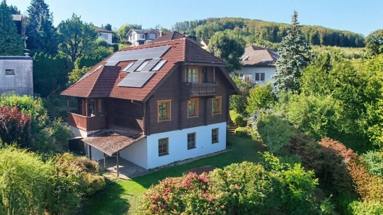 Freistehendes Haus mit Photovoltaikanlage, umgeben von üppigem Grün und Bäumen in ländlicher Umgebung.