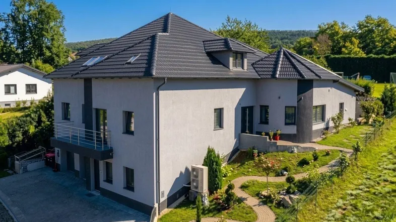Modernes Einfamilienhaus mit gepflegtem Garten und Balkon in sonniger Hanglage.