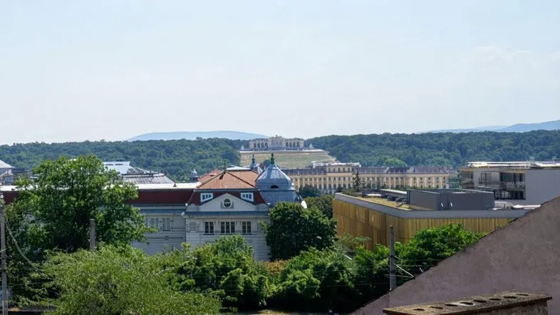 Weitblick über die Stadt mit dem Schloss Schönbrunn und der Gloriette auf einem bewaldeten Hügel.