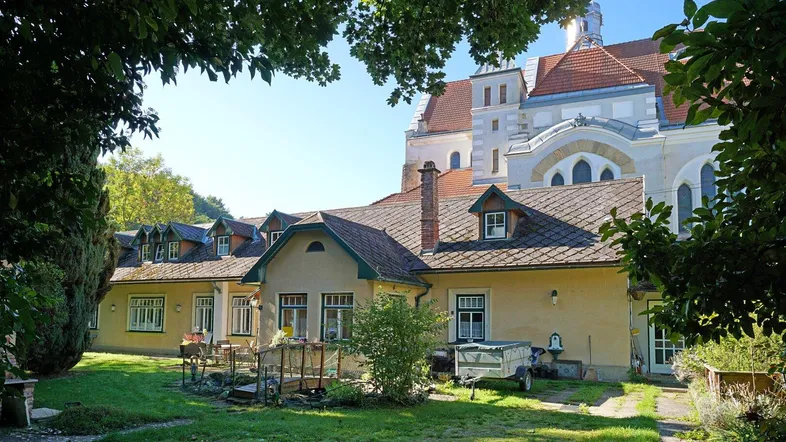 Rückseite des Hauses mit gepflegtem Garten, kleiner Terrasse und Blick auf das historische Gebäude.