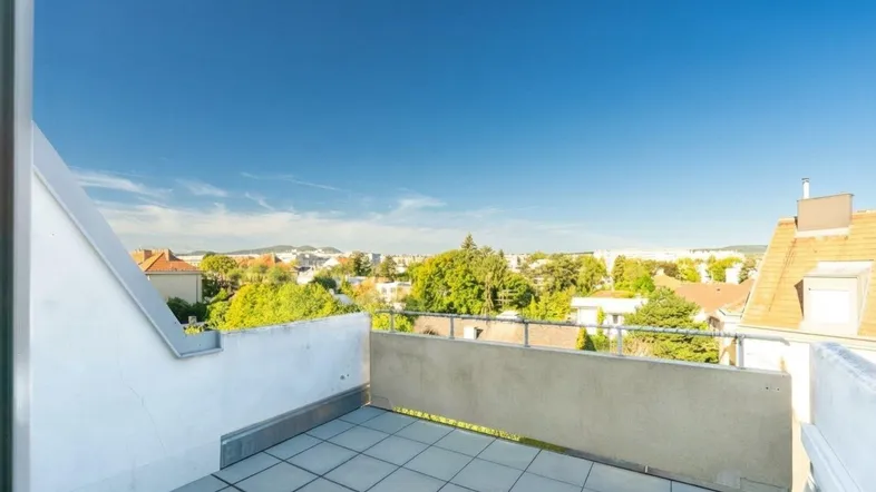 Geräumiger Balkon mit Fliesenboden und weitem Blick über die Stadt und grüne Umgebung.