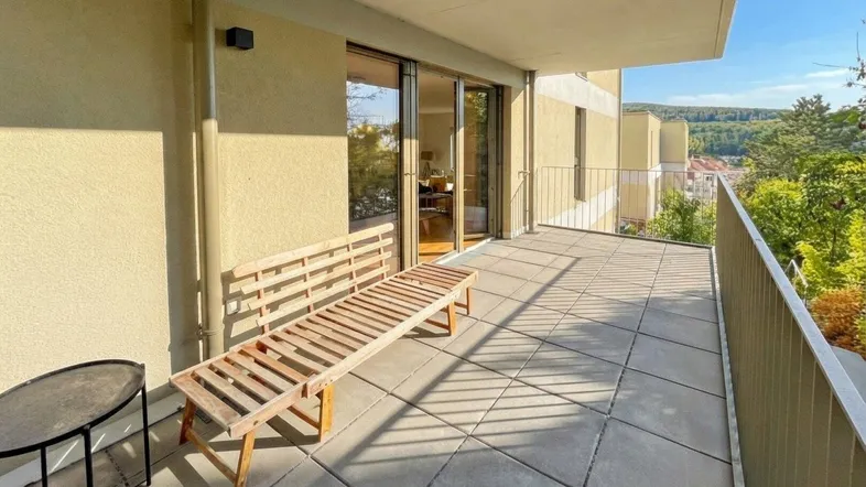 Geräumiger Balkon mit Holzsitzbank und weitem Blick ins Grüne.