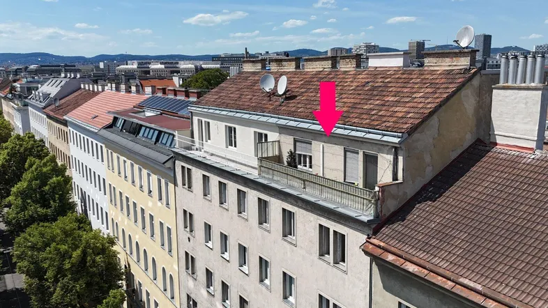Luftaufnahme eines Wohngebäudes mit einem Balkon im Dachgeschoss und weitem Stadtblick.