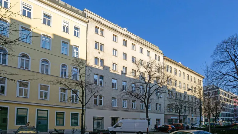 Mehrere Wohngebäude mit klassischer Fassade und Fenstern entlang einer städtischen Straße.