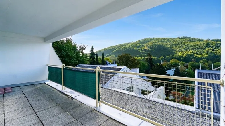 Geräumiger Balkon mit Fliesenboden und weitem Blick auf grüne Hügel und die Umgebung.