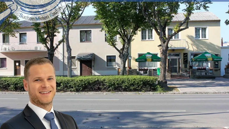 Gebäudeansicht mit Straße und einem Immobilienmakler im Vordergrund.