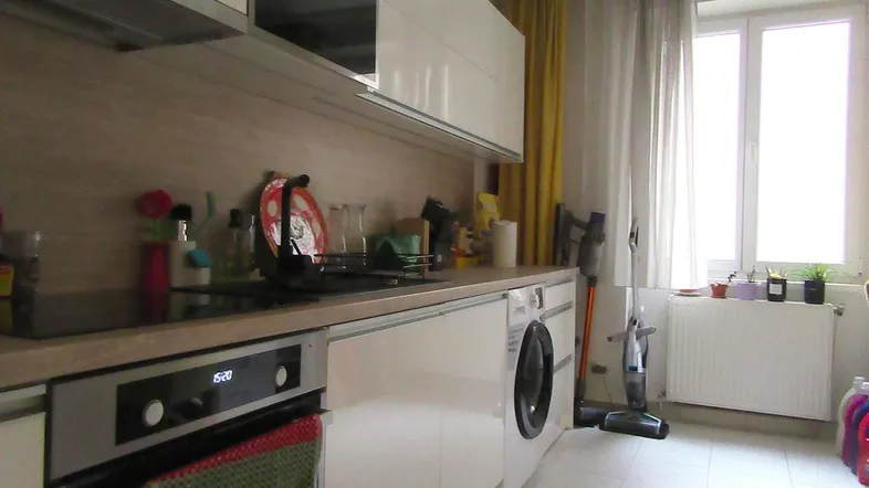 Moderne Küche mit weißen Hochglanzfronten, integrierten Geräten und einem Fenster für natürliches Licht.