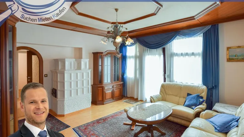 Gemütliches Wohnzimmer mit traditionellem Kachelofen, Holzelementen und großen Fenstern.