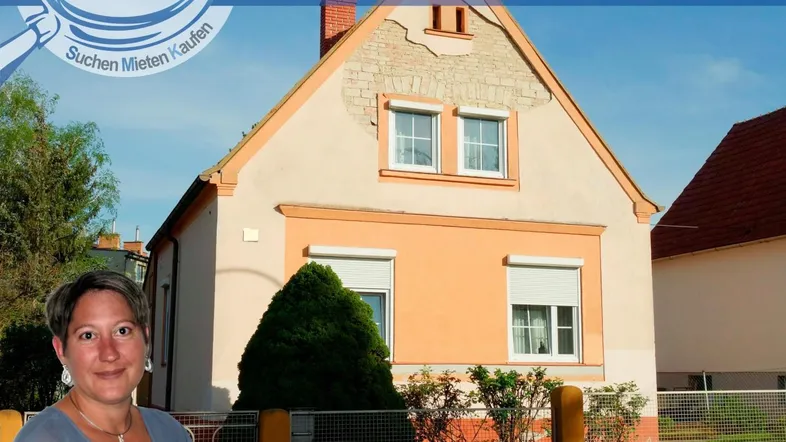 Einfamilienhaus mit orangefarbener Fassade und Giebeldach, umgeben von Grünflächen.