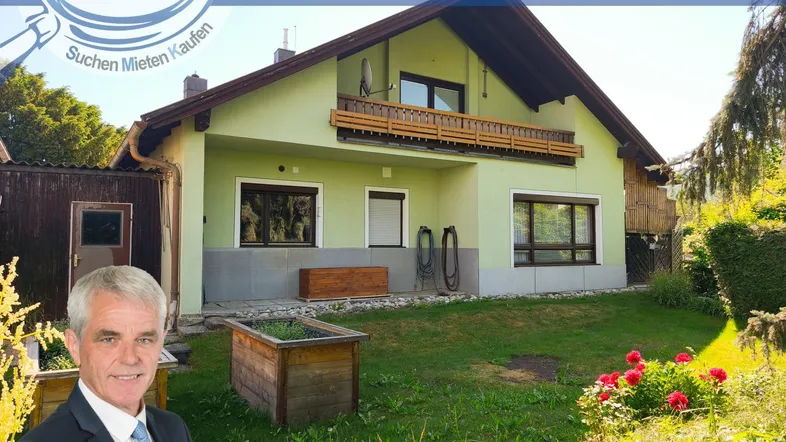 Hausfassade mit Gartenbereich und gepflegter Grünfläche, umgeben von Bäumen und Sträuchern.