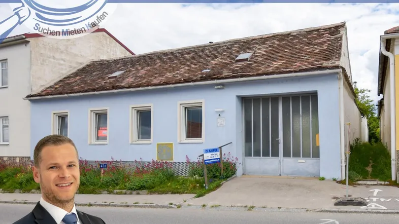 Gebäudeansicht eines älteren Hauses mit Garage und hellblauer Fassade im ländlichen Stil.