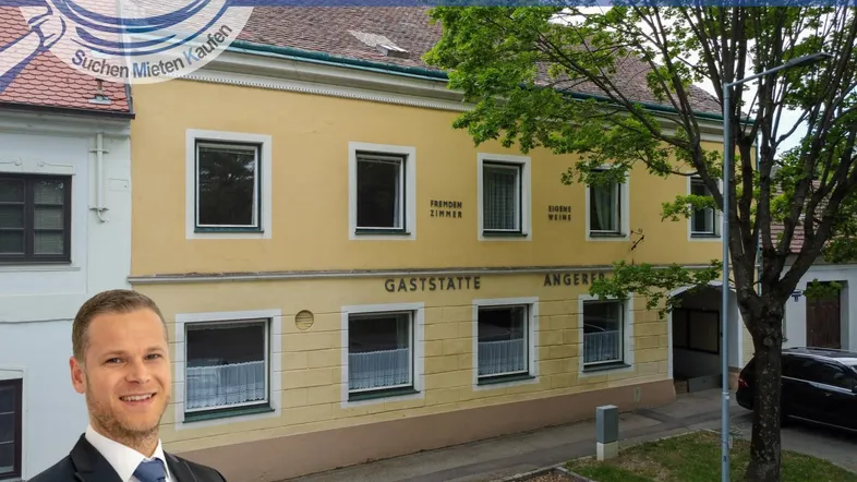 Gelbe Fassade eines Gasthauses mit Fenstern und Beschriftung, umgeben von Bäumen.
