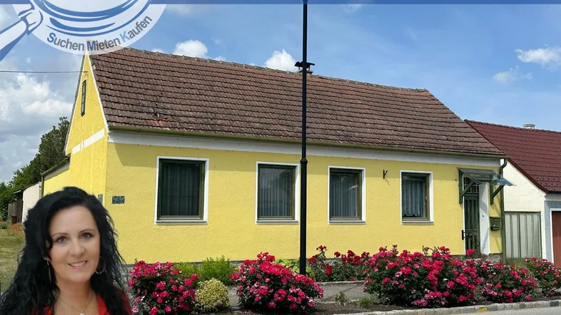 Gelbes Einfamilienhaus mit rotem Ziegeldach und blühenden Rosen im Vorgarten.