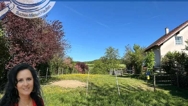 Weitläufiges Grundstück mit grüner Wiese, Bäumen und einem Haus im Hintergrund unter blauem Himmel.