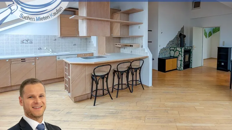 Geräumige offene Wohnküche mit Holzmöbeln, Kücheninsel und Kaminofen im Dachgeschoss.