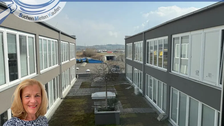 Blick auf die moderne Gebäudefassade mit vielen Fenstern und einem begrünten Innenhof. Eine Frau ist im Vordergrund sichtbar.
