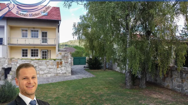 Gepflegter Gartenbereich mit Bäumen und einem Teil der Hausfassade im Hintergrund.