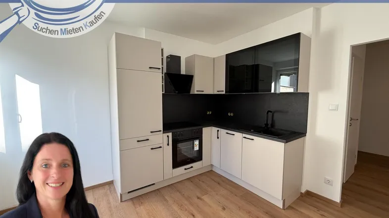 Moderne Einbauküche mit hellgrauen Schränken, schwarzer Arbeitsplatte und integriertem Backofen.