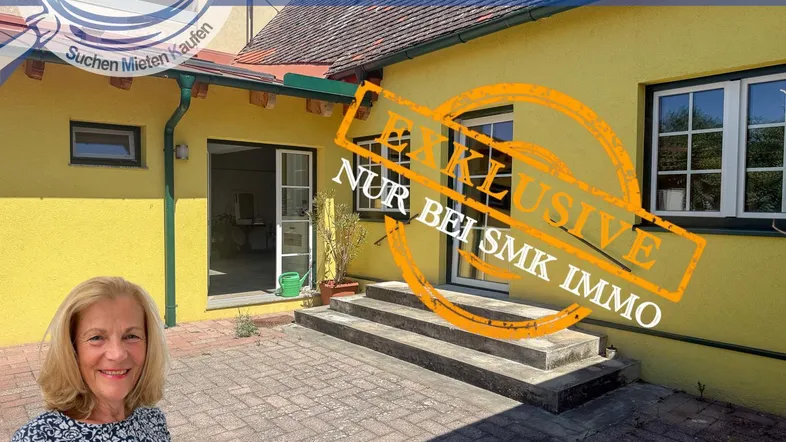 Gelbes Haus mit gepflasterter Terrasse und Zugang zum Innenbereich, teilweise verdeckt durch Werbung.
