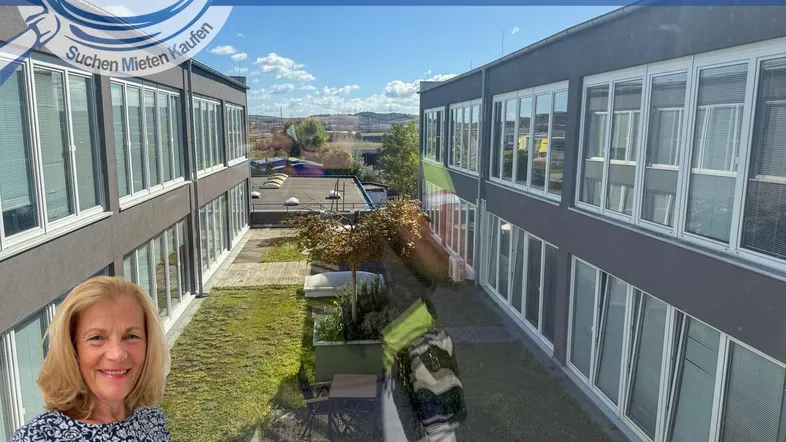 Außenansicht eines modernen Gebäudes mit vielen Fenstern und begrüntem Innenhof.