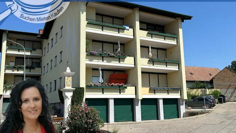 Mehrfamilienhaus mit mehreren Balkonen und Garagen, umgeben von Grünflächen.
