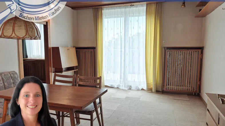 Gemütlicher Wohn-Essbereich mit Holztisch, Stühlen und Blick nach draußen durch große Fenster.