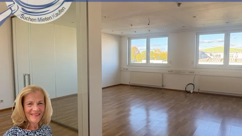 Leerer Raum mit hellem Holzfußboden, großen Fenstern und einer modernen Glaswand.