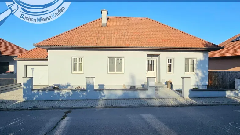 Vorderansicht eines Einfamilienhauses mit Satteldach und integrierter Garage in gutem Zustand.
