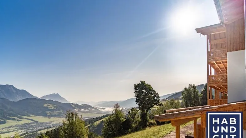 Sonnige Berglandschaft mit einem Teil des Gebäudes und weitem Blick ins Tal.