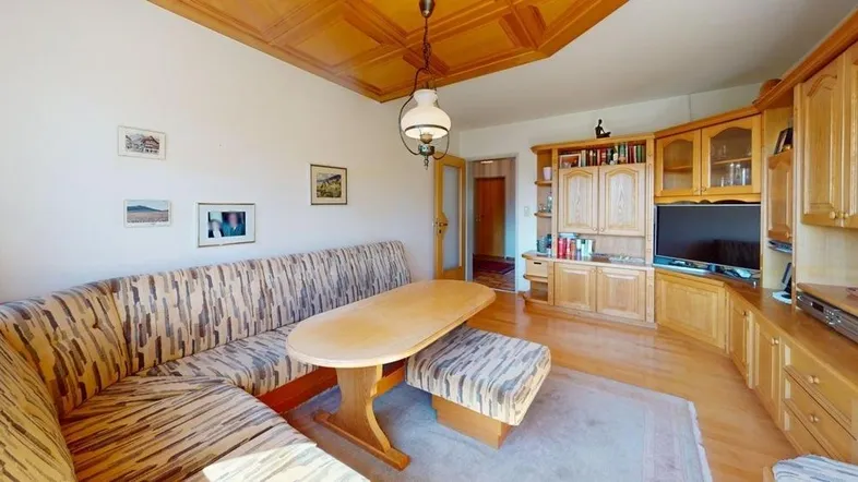 Helles Wohnzimmer mit Holzdecke, Eckbank und traditionellen Holzmöbeln.