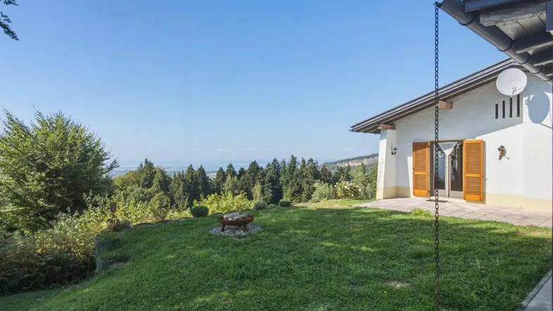 Großer Garten mit Rasenfläche, Feuerstelle und weitem Blick auf die Landschaft und das Wasser.