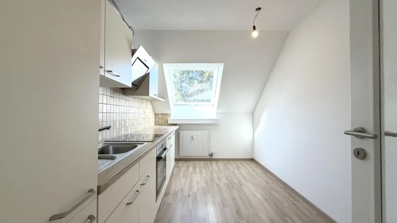 Helle Küche mit Dachschräge, Einbauküche und Laminatboden, ausgestattet mit modernen Geräten.